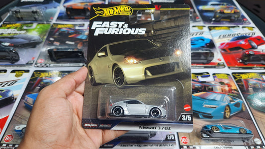 Hot Wheels Fast & Furious toy car packaging held by a hand with more packages in the background.